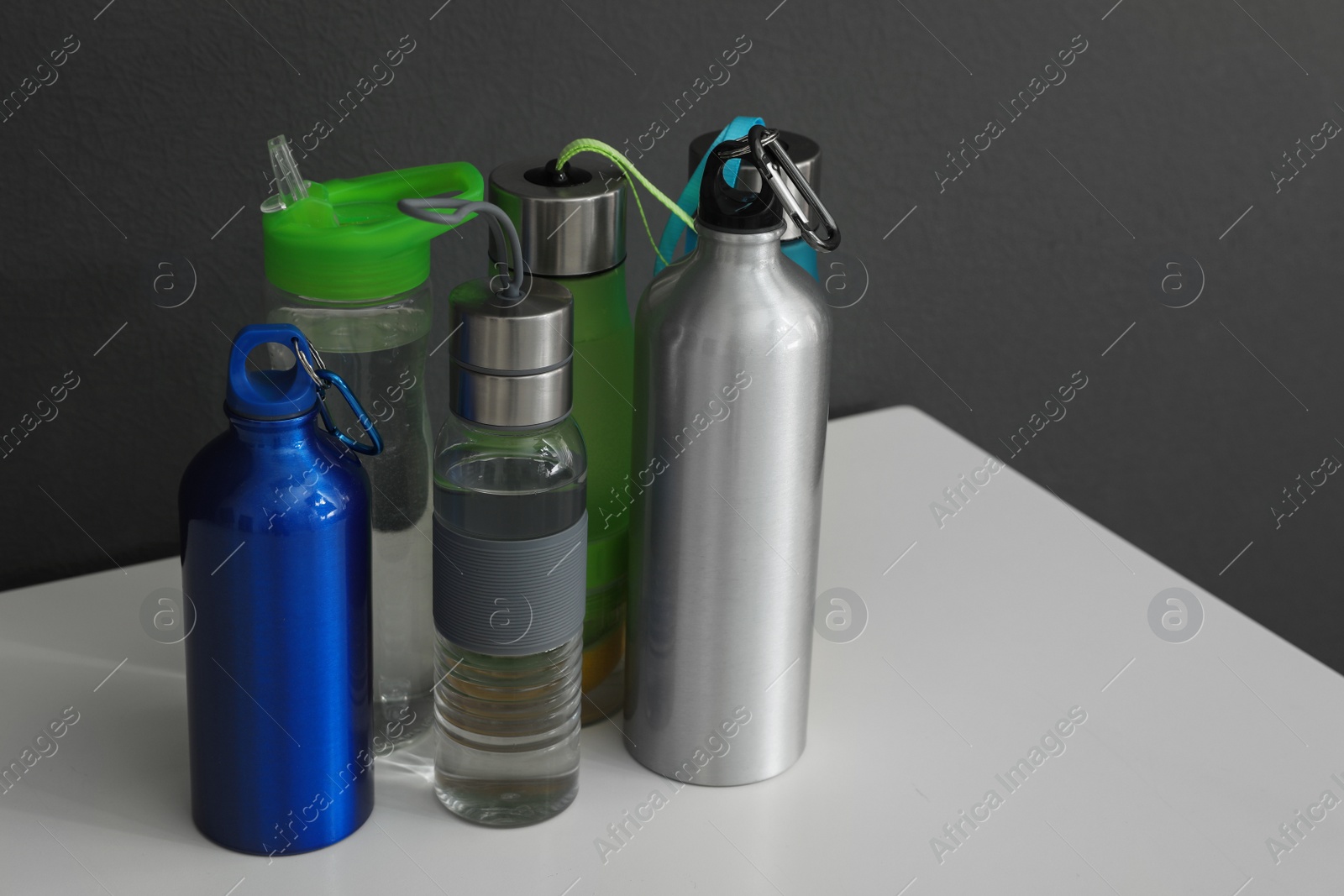 Photo of Different water bottles for sports on gray background