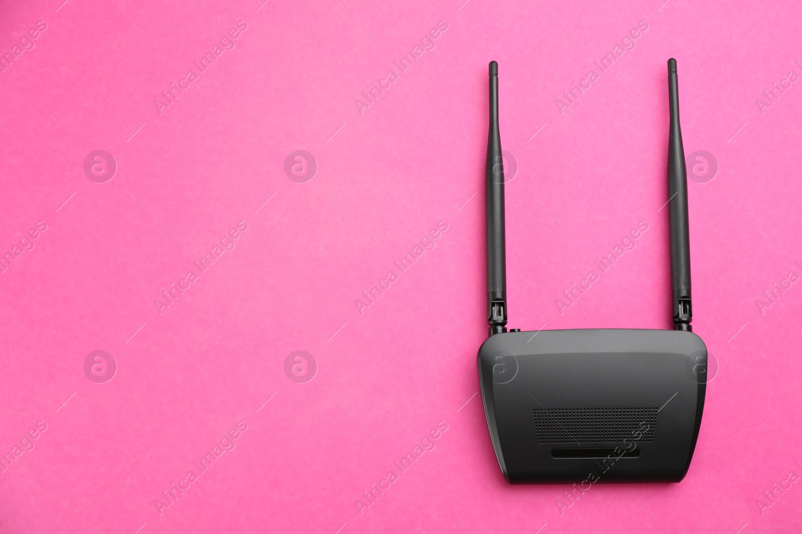 Photo of Modern Wi-Fi router on pink background, top view. Space for text