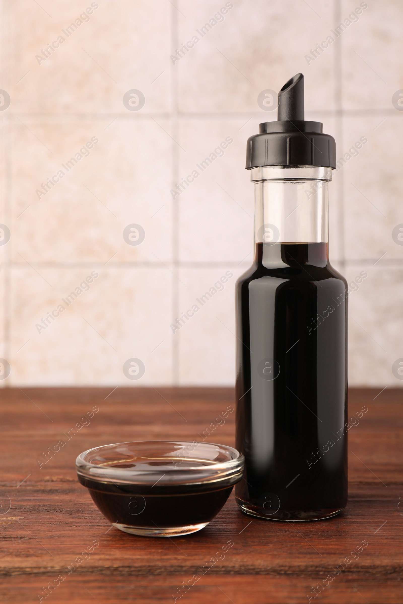 Photo of Bottle and bowl with soy sauce on wooden table