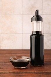 Bottle and bowl with soy sauce on wooden table
