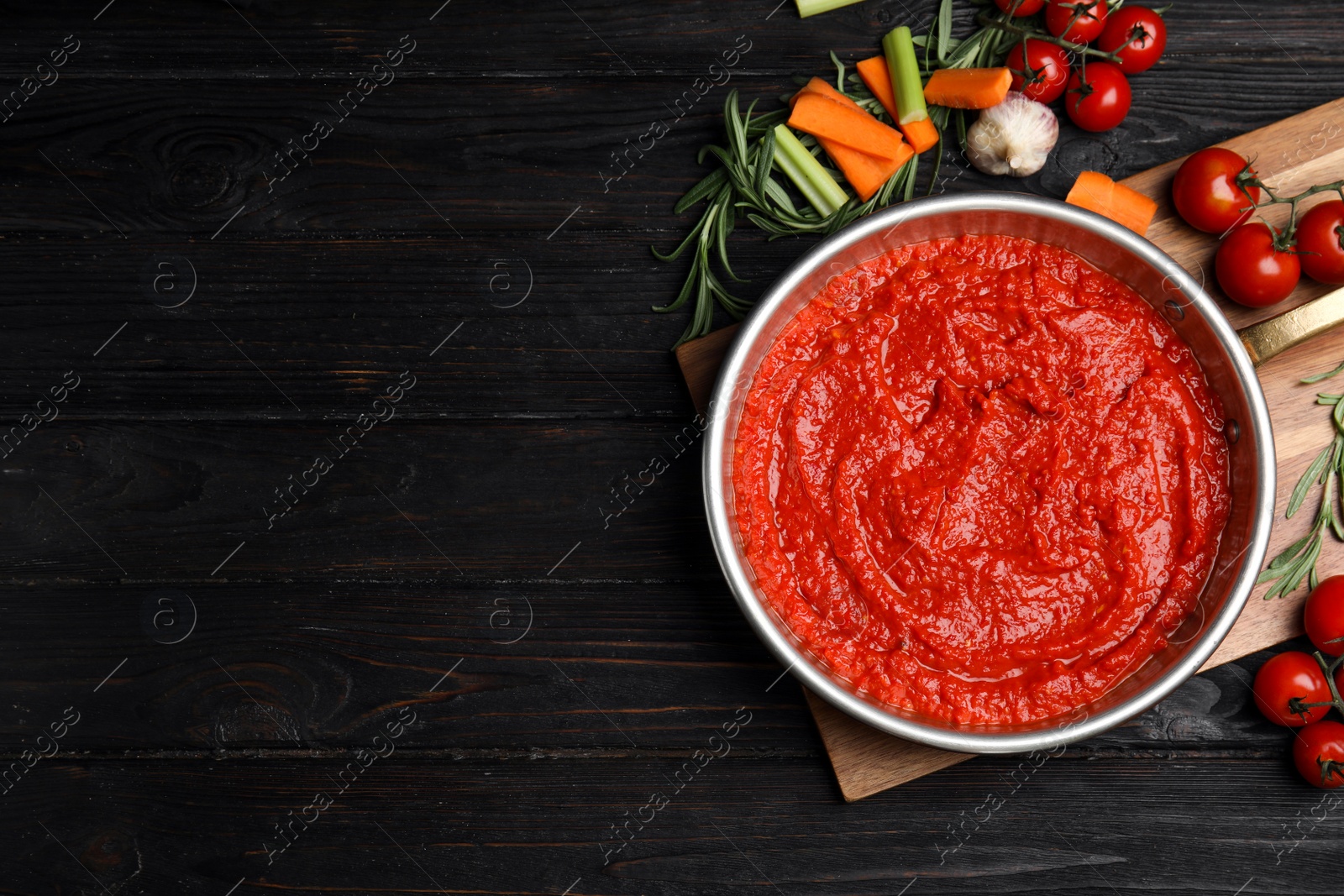 Photo of Flat lay composition with delicious tomato sauce on black wooden table. Space for text