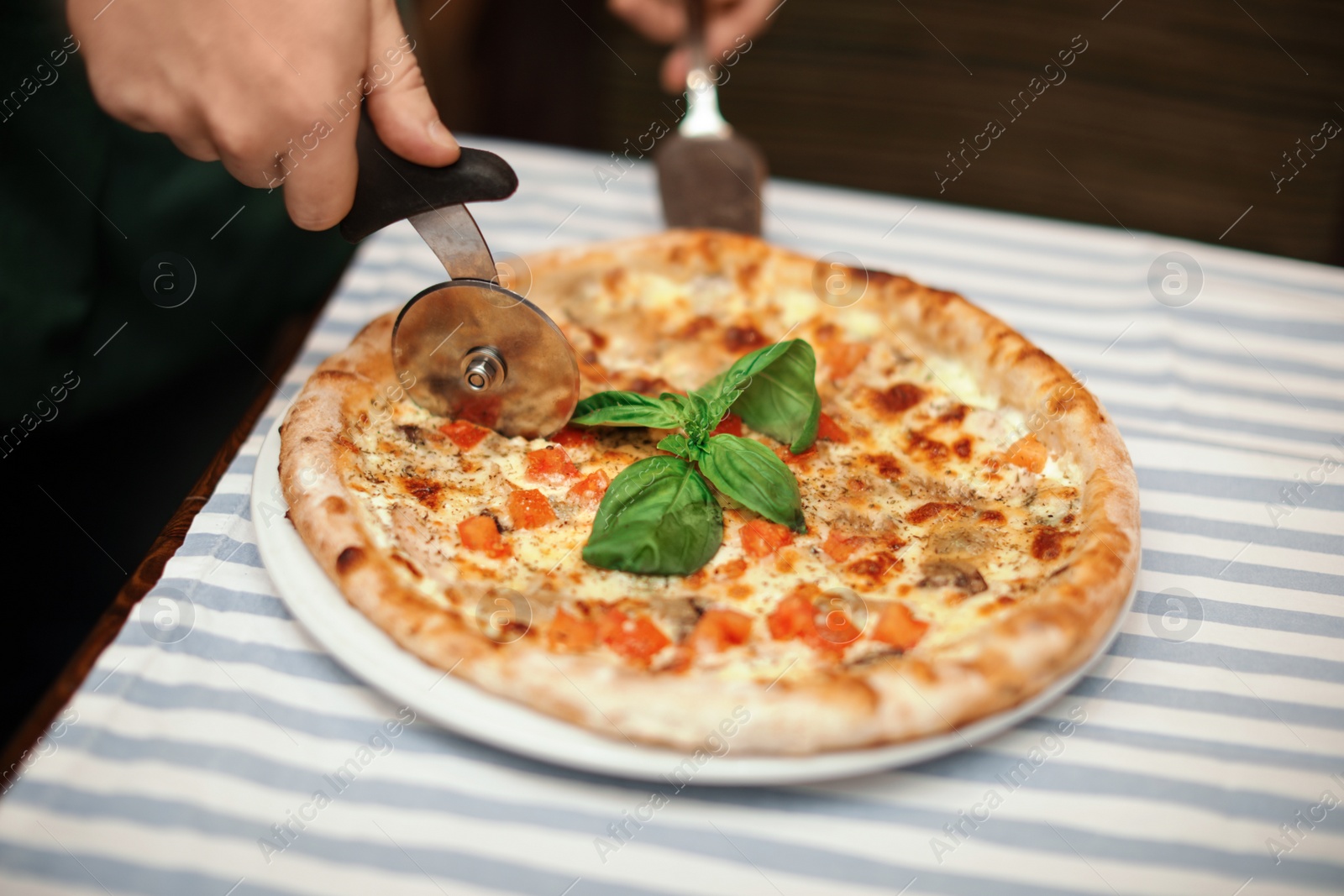 Photo of Man cutting tasty oven baked pizza on table, closeup