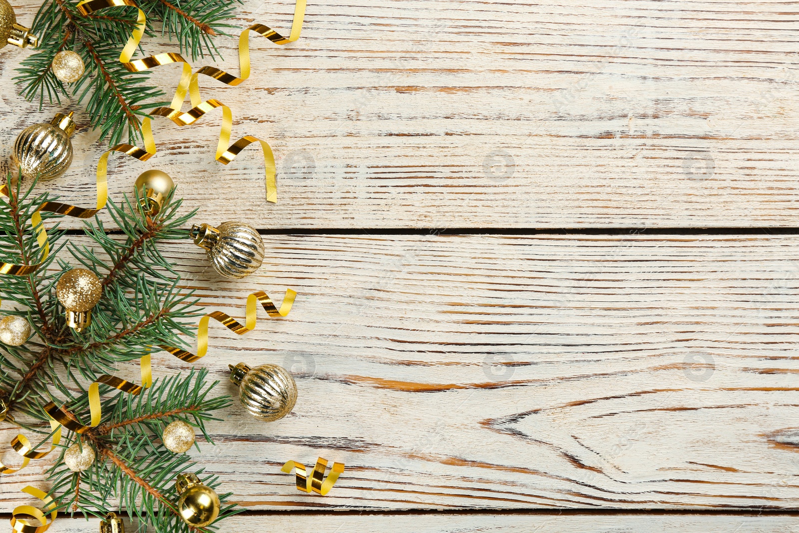 Photo of Shiny serpentine streamers, Christmas balls and fir branches on white wooden background, flat lay. Space for text