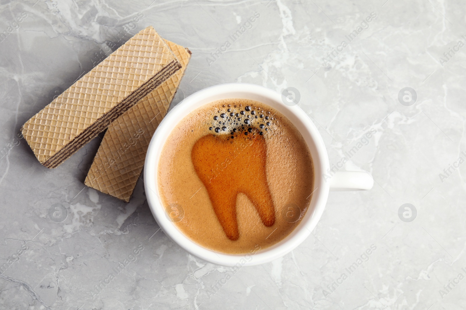 Image of Coffee causing dental problem. Cup of hot drink and wafers on grey marble table, flat lay