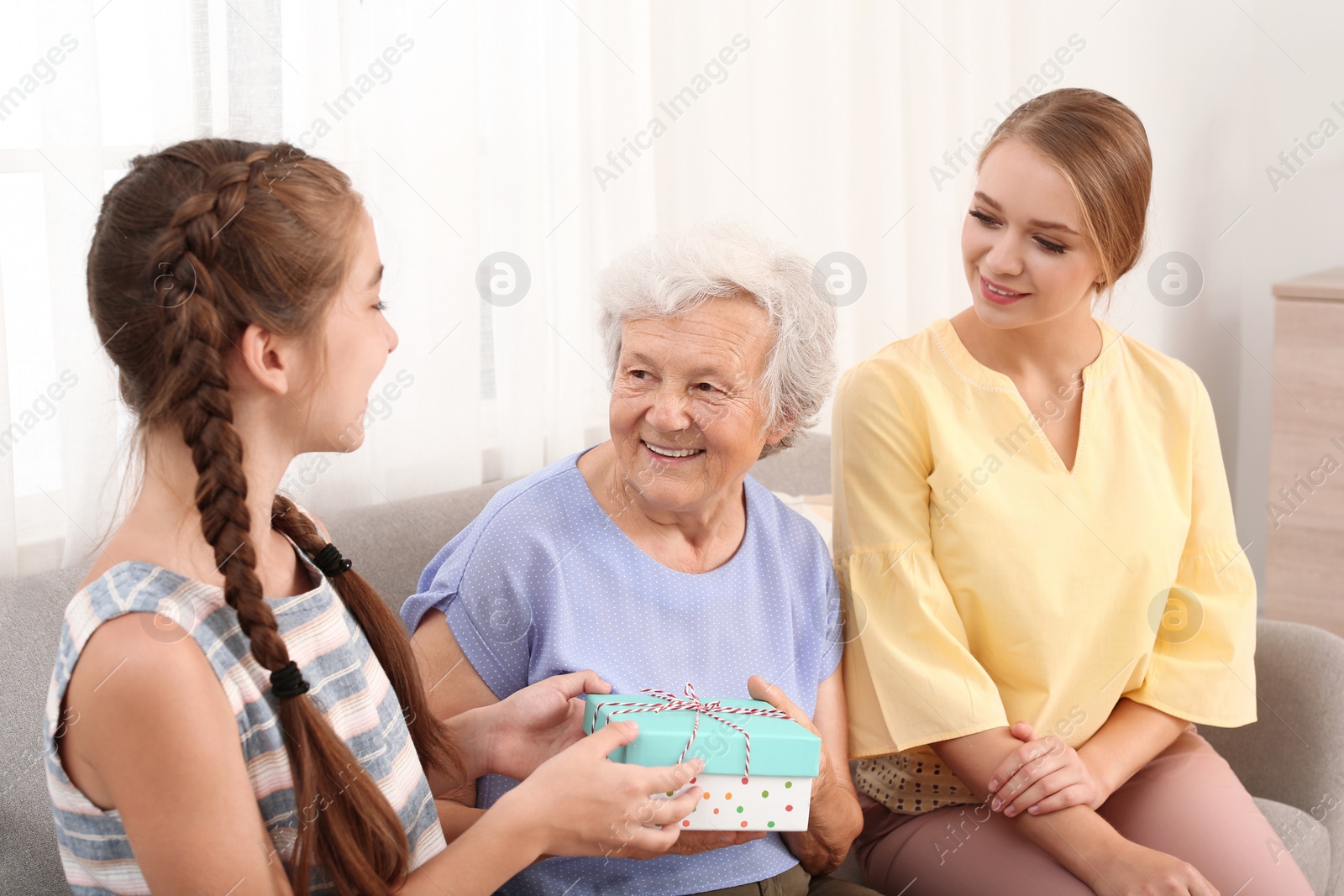 Photo of Happy sisters congratulating their grandmother at home