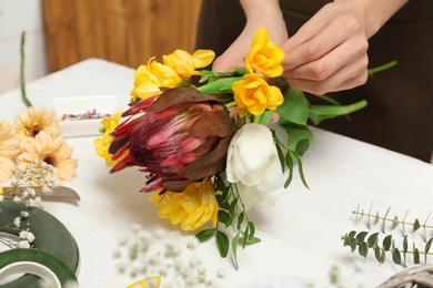 Female florist making beautiful bouquet at table