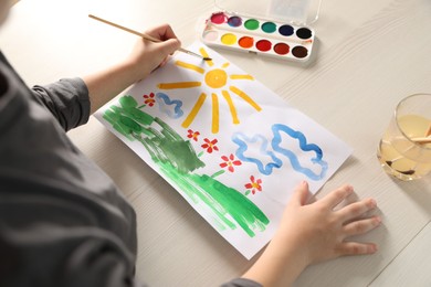 Photo of Little boy drawing picture at wooden table, above view. Child`s art