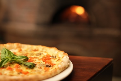 Photo of Tasty oven baked pizza on wooden table, closeup. Space for text