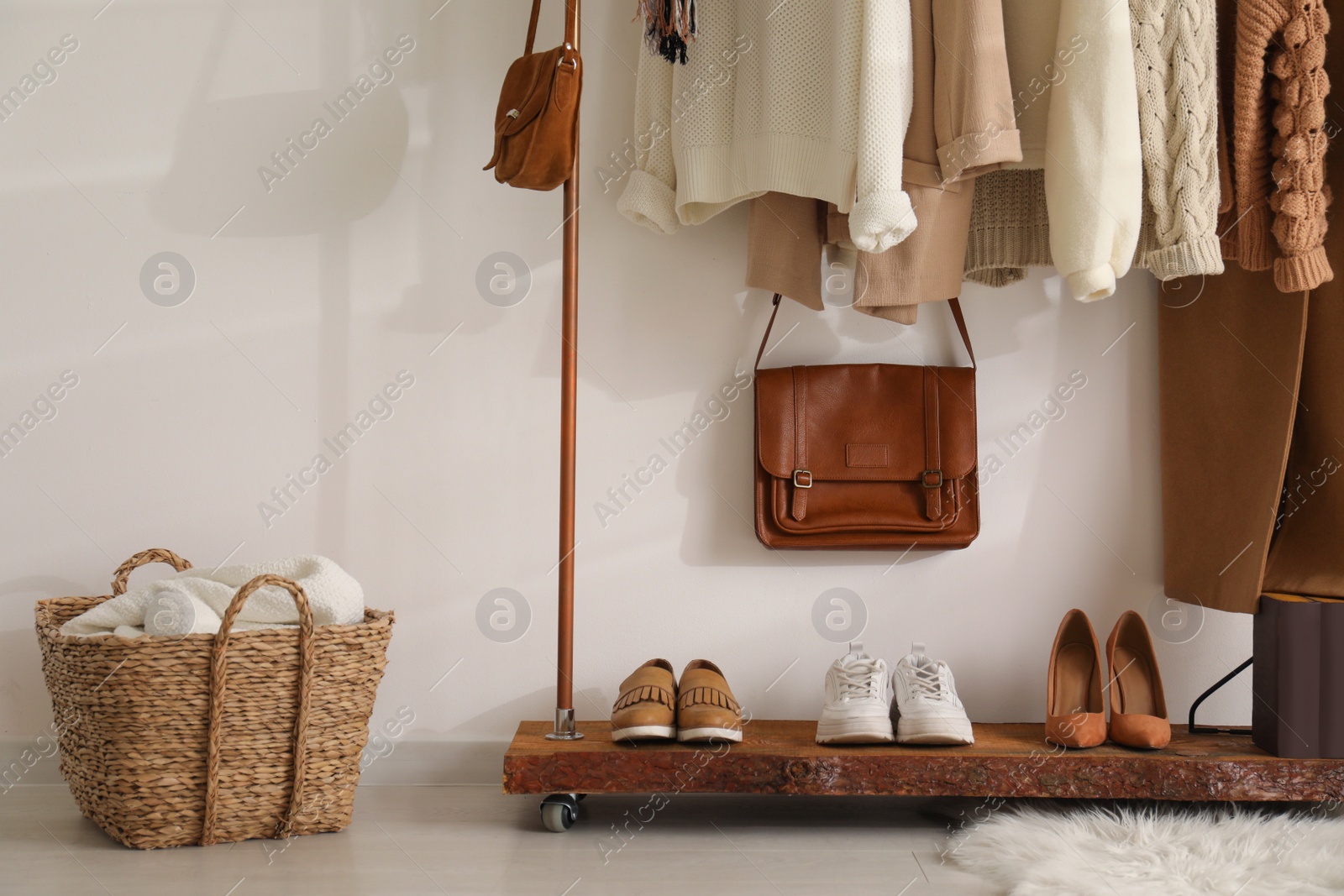 Photo of Rack with stylish shoes and women's clothes in dressing room. Modern interior design