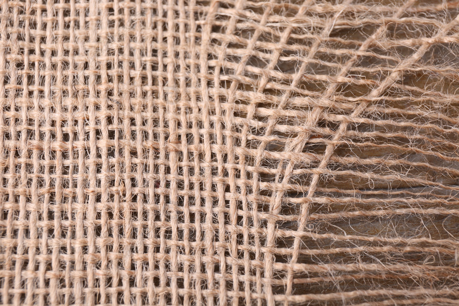 Photo of Piece of burlap fabric on wooden table, top view