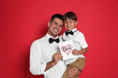 Photo of Little boy greeting his dad with Father's Day on red background