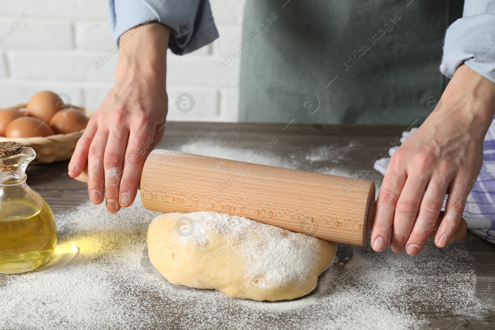 Photo of Woman rolling raw dough at table, closeup