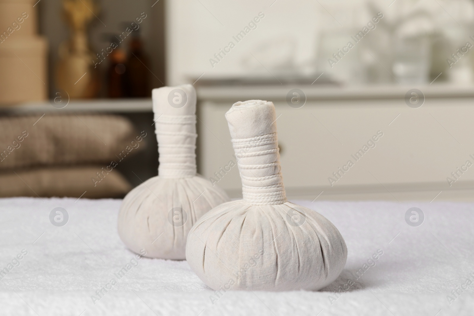 Photo of Herbal massage bags on white towel indoors. Spa procedure