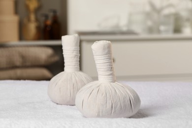 Photo of Herbal massage bags on white towel indoors. Spa procedure