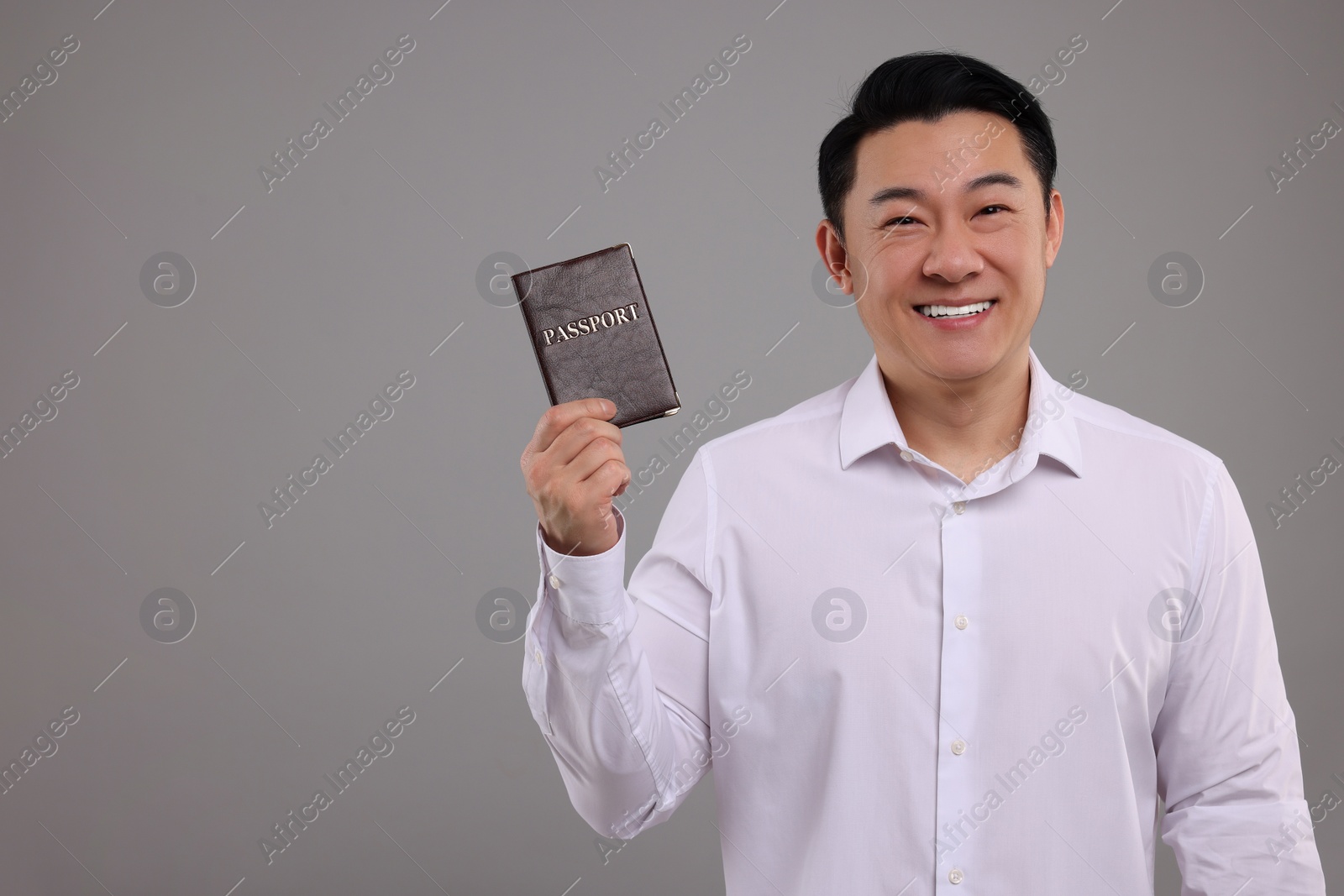 Photo of Immigration. Happy man with passport on grey background, space for text