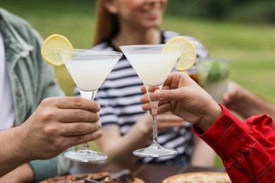 Photo of Friends clinking glasses with cocktails outdoors, closeup