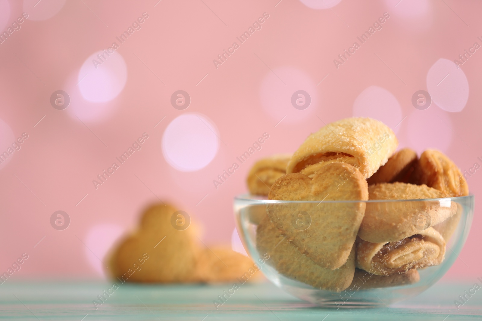 Photo of Delicious cookies in bowl on table against blurred background, closeup. Space for text