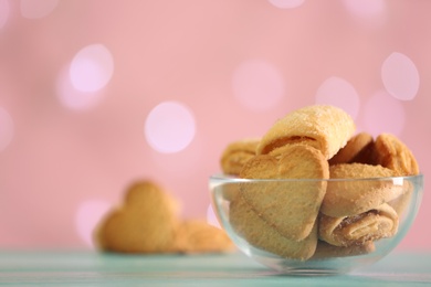 Photo of Delicious cookies in bowl on table against blurred background, closeup. Space for text