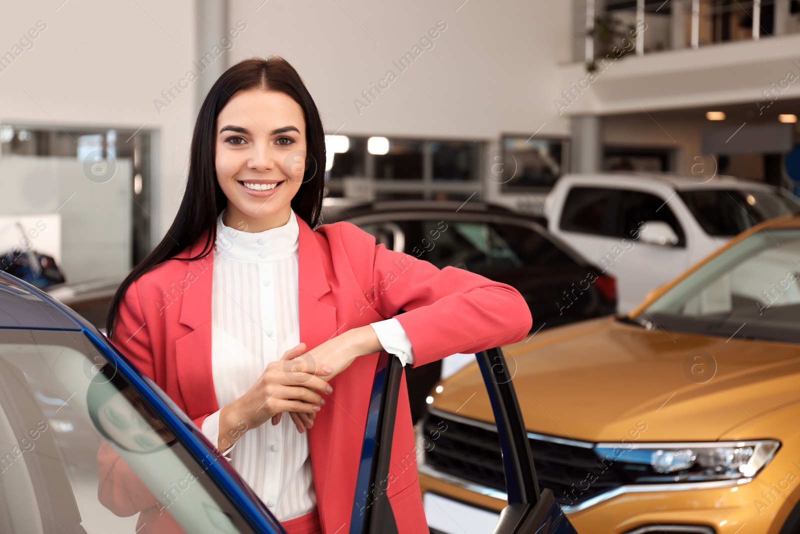 Photo of Young saleswoman near new car in dealership