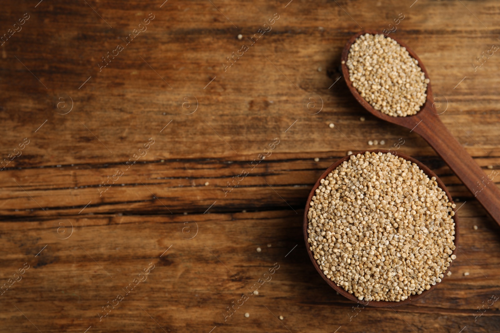 Photo of Bowl and spoon with white quinoa on wooden table, flat lay. Space for text