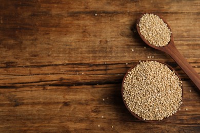 Photo of Bowl and spoon with white quinoa on wooden table, flat lay. Space for text