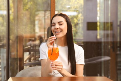 Photo of Young woman drinking Aperol spritz cocktail at outdoor cafe