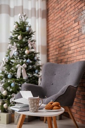 Photo of Book with treat on table and Christmas tree in stylish living room interior