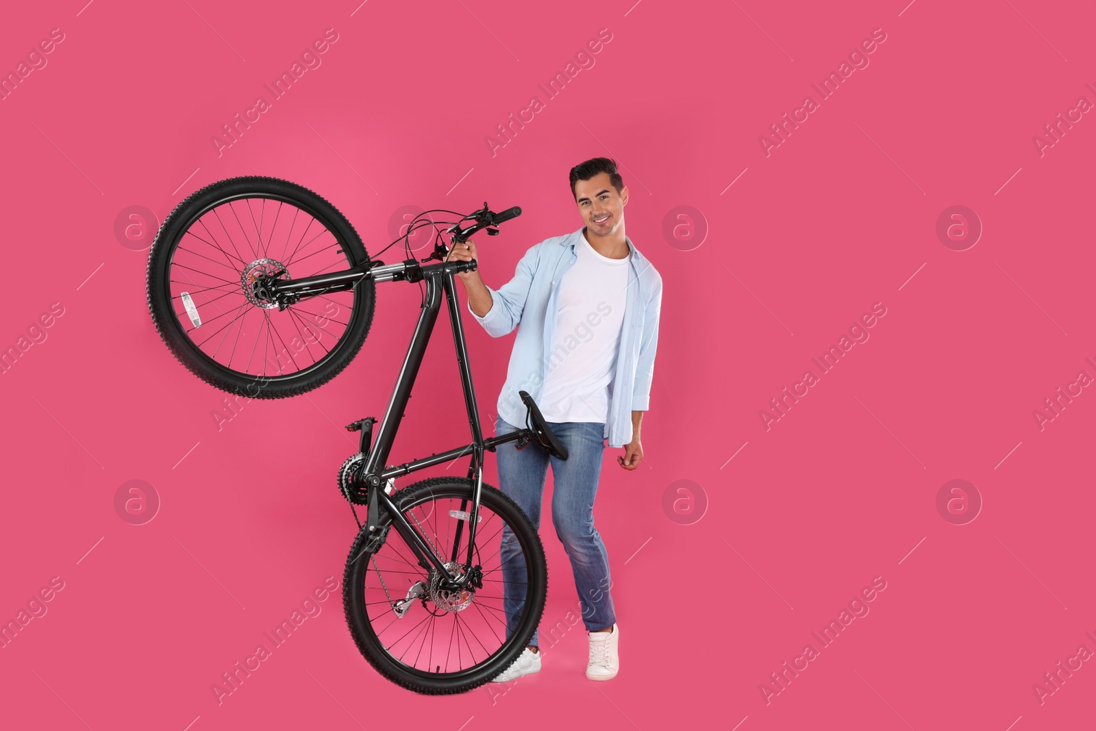 Photo of Handsome young man with modern bicycle on pink background