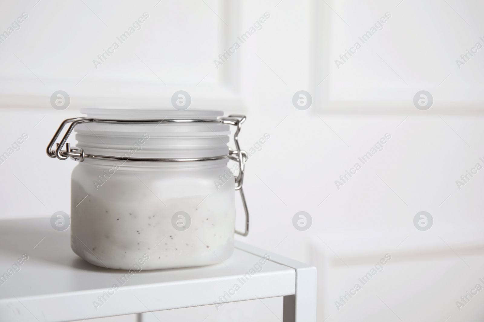 Photo of Jar of salt scrub on white table. Space for text