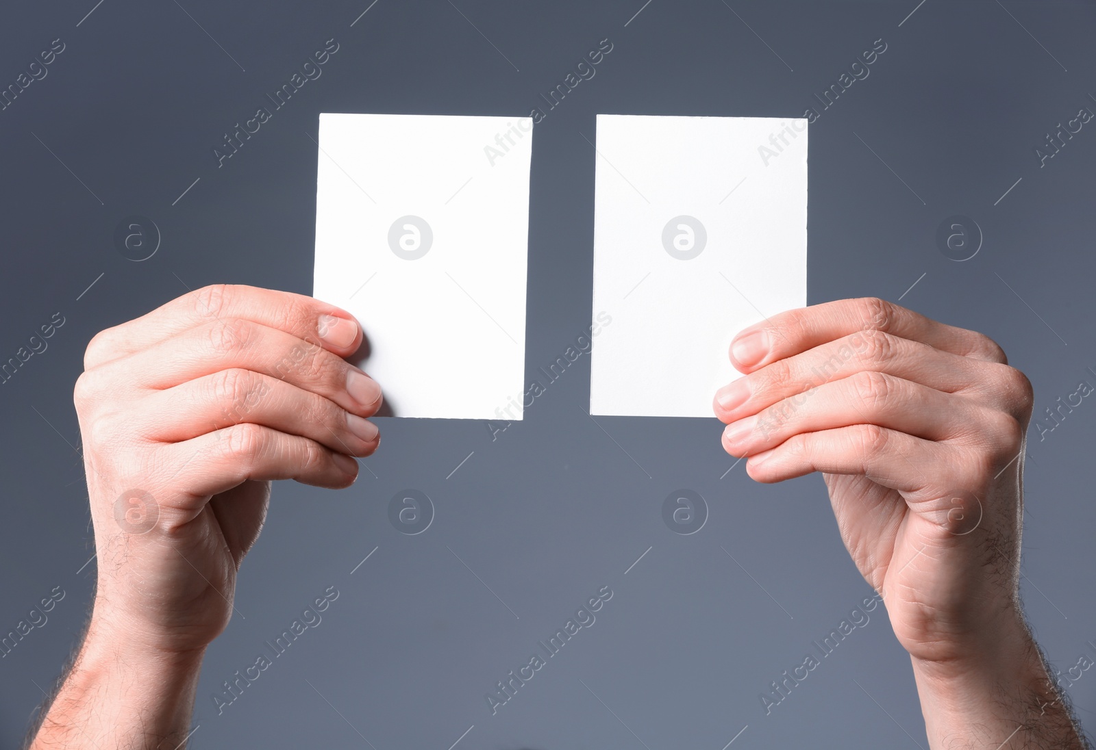 Photo of Man holding paper cards on grey background, closeup. Mockup for design