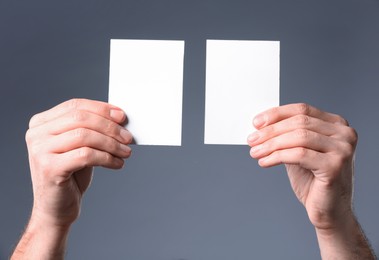 Photo of Man holding paper cards on grey background, closeup. Mockup for design