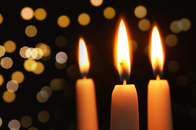 Image of Burning candles on dark background with blurred lights, closeup. Bokeh effect