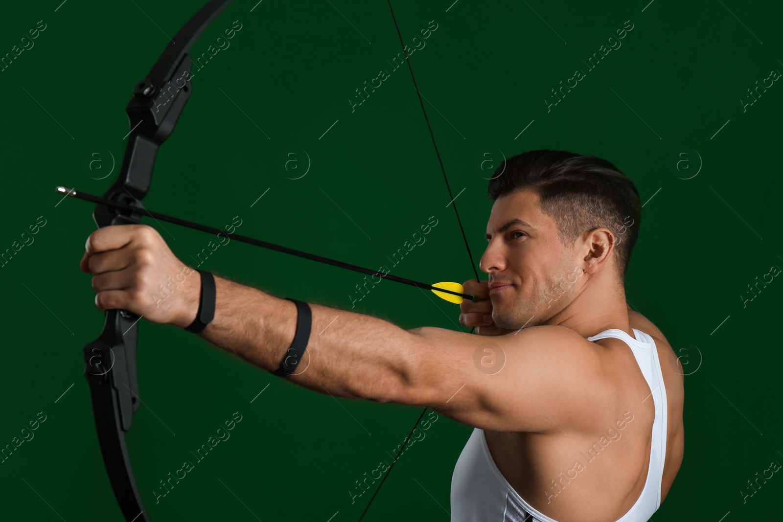 Photo of Man with bow and arrow practicing archery on green background