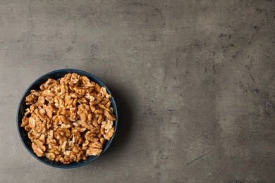 Photo of Dish with walnuts on grey background, top view. Space for text