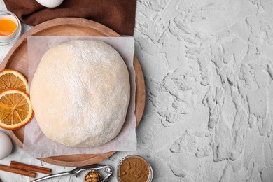 Fresh dough and cooking ingredients in white textured table, flat lay. Space for text