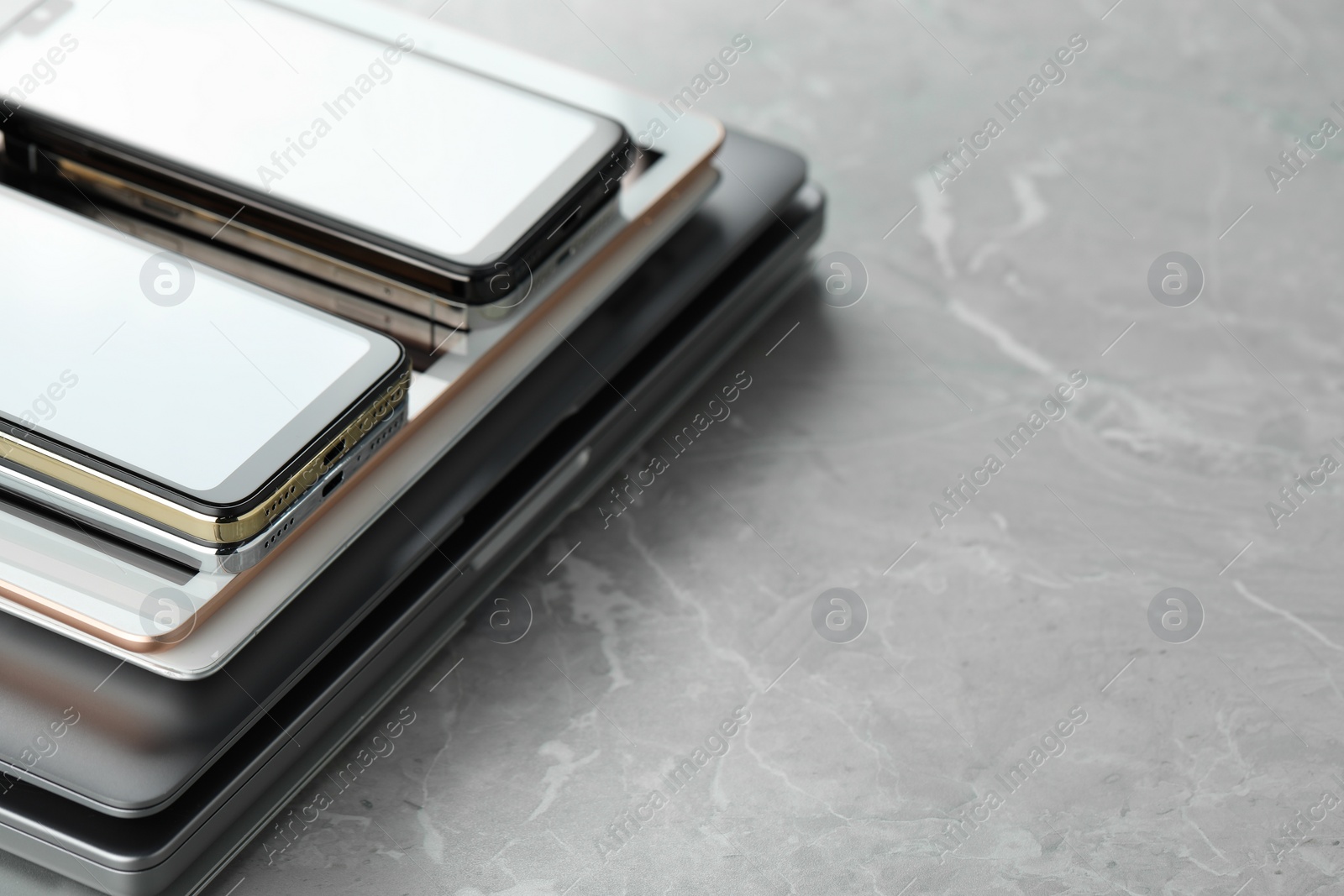 Photo of Stack of electronic devices on grey stone table, closeup. Space for text