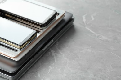 Photo of Stack of electronic devices on grey stone table, closeup. Space for text