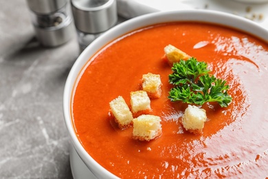 Photo of Bowl with fresh homemade tomato soup on table, closeup