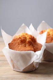 Photo of Delicious sweet muffins on wooden table against grey background, closeup