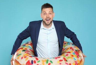 Photo of Funny businessman with bright inflatable ring on blue background