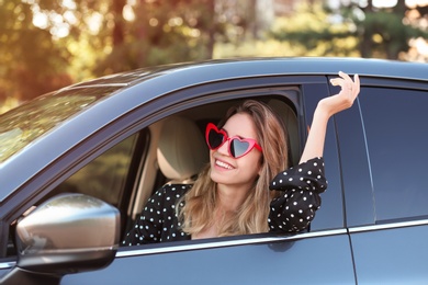 Young beautiful woman wearing heart shaped glasses in car