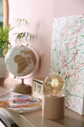 Photo of Modern night lamp and decor on table near pink wall