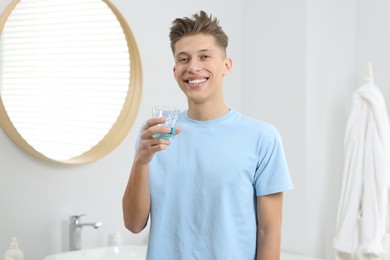 Photo of Young man with mouthwash in bathroom. Oral hygiene