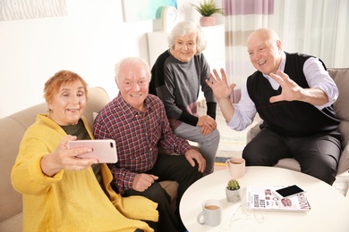 Elderly people taking selfie at table in living room