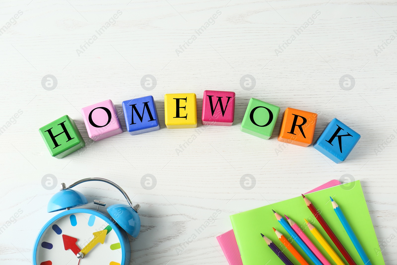 Photo of Flat lay composition with word HOMEWORK made of black cubes on white wooden table