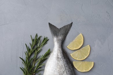Photo of Fresh raw dorado fish, lemon slices and rosemary on grey table, flat lay