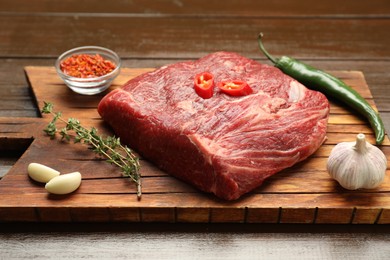 Photo of Fresh raw beef cut with spices on wooden table