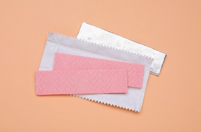 Photo of Sticks of tasty chewing gum on coral background, flat lay