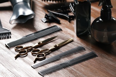 Photo of Hairdresser tools. Different scissors and combs on wooden table, closeup