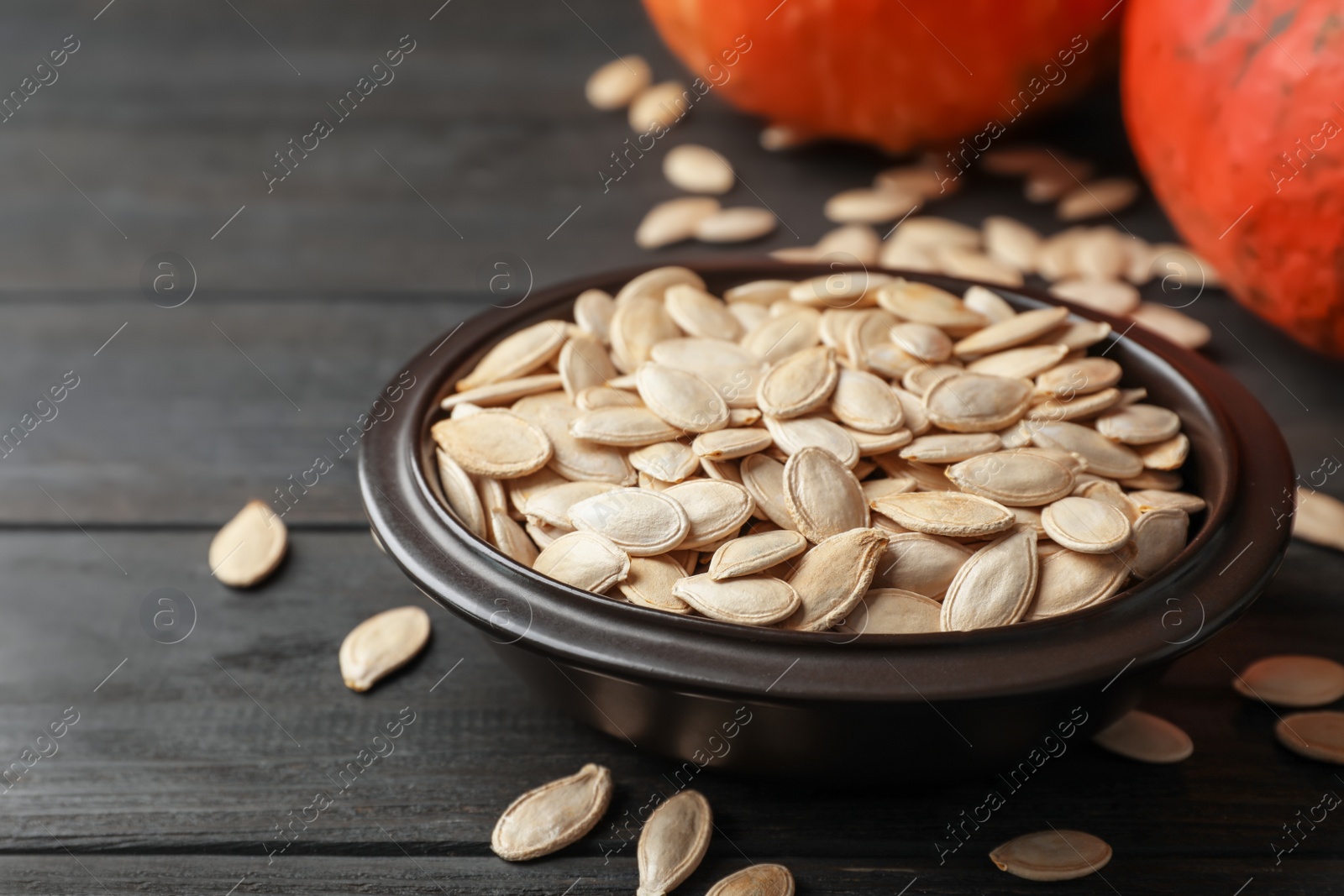 Photo of Full bowl of raw pumpkin seeds on wooden table